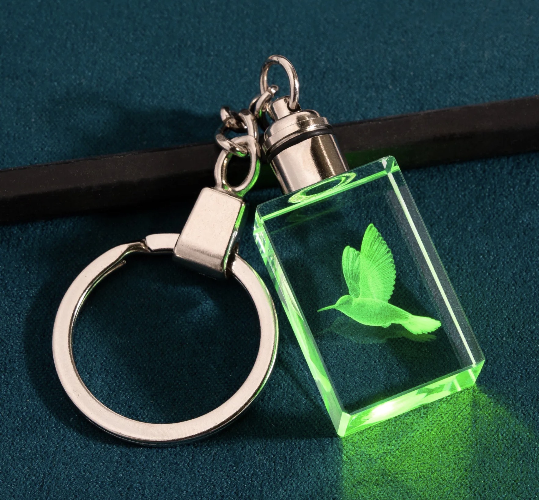 Rectangular crystal keychain with a hummingbird engraved inside, lit green