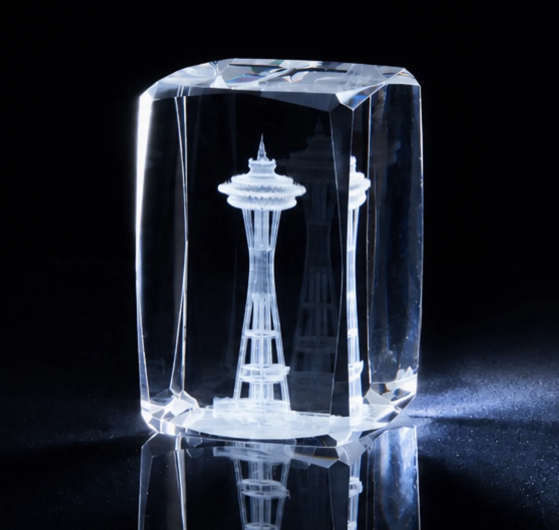 Beveled crystal block with a detailed tower engraved inside, lit against a dark background