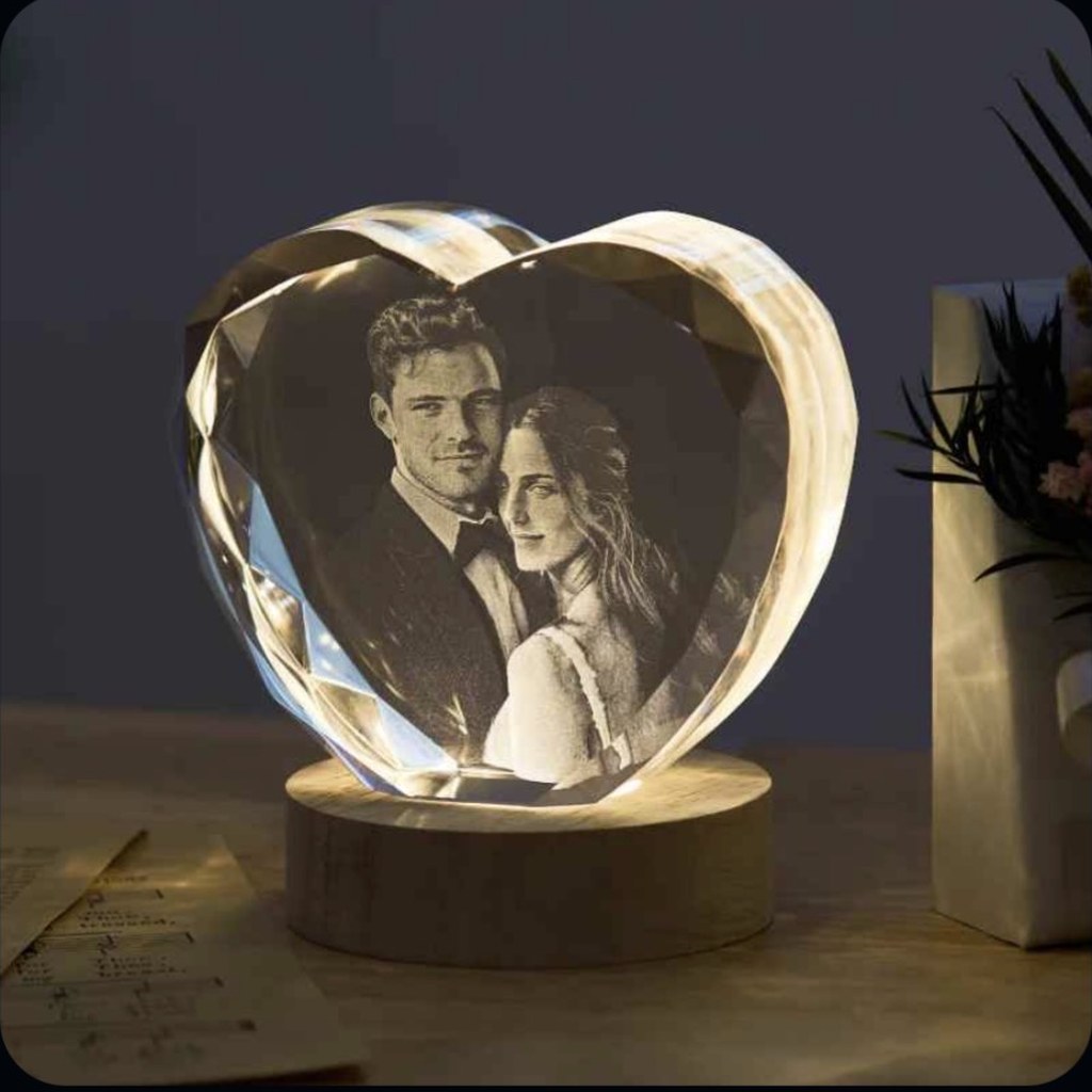 Faceted heart crystal with a photo of a couple etched inside, lit from below